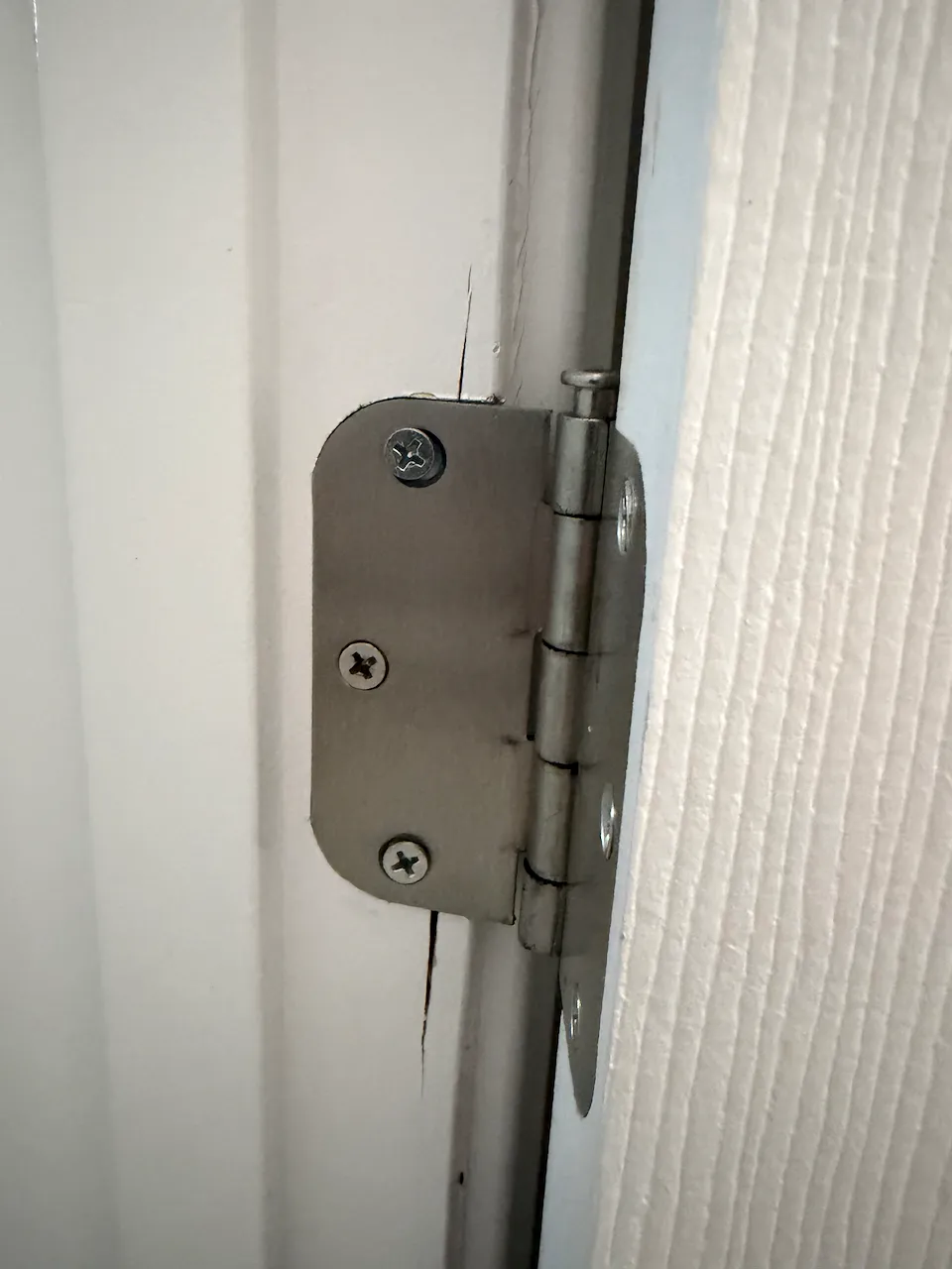 Cracked door frame at hinge screw locations